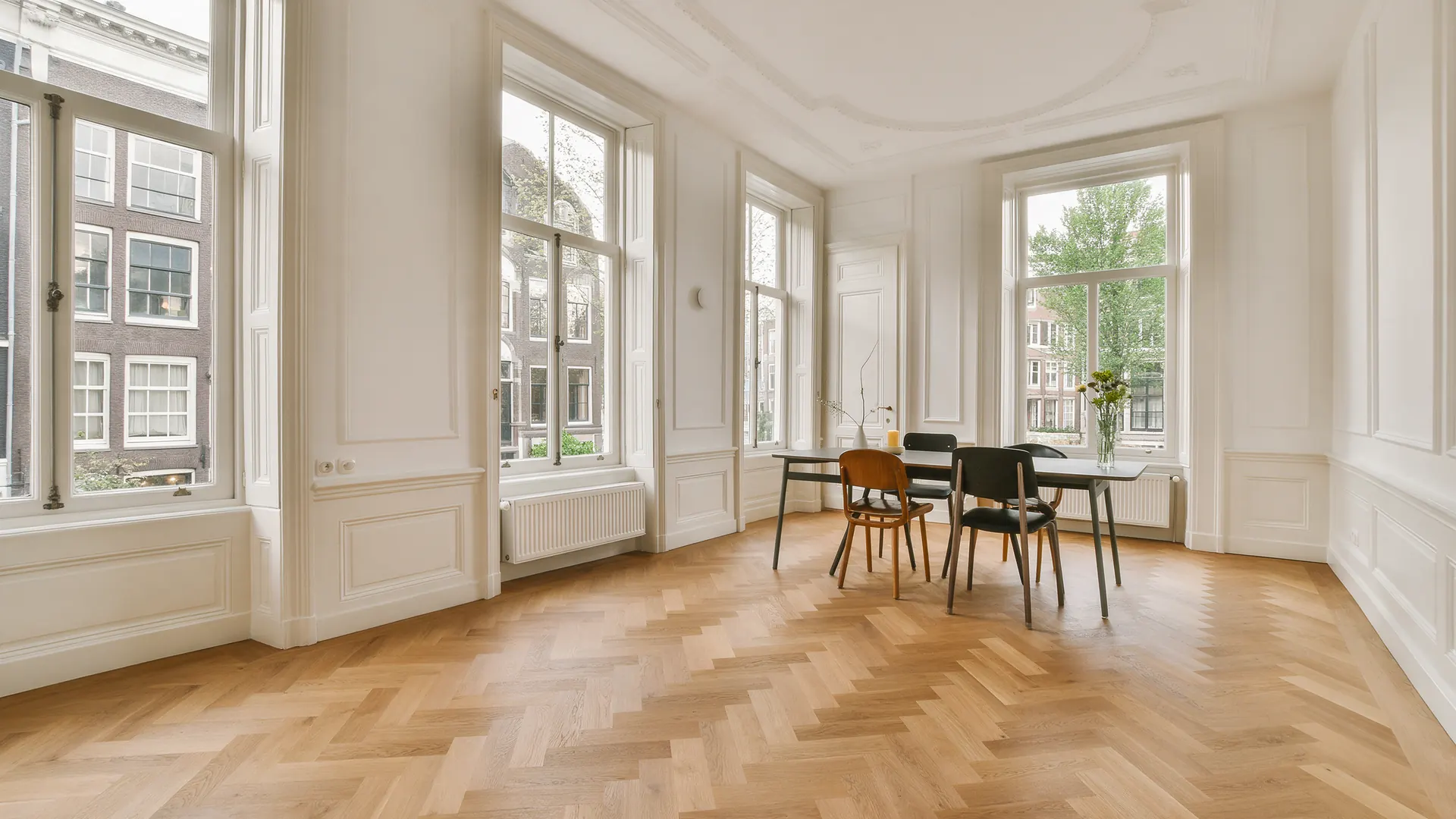 Eetkamer in een grachtenpand met een eiken visgraat parketvloer en hoge ramen